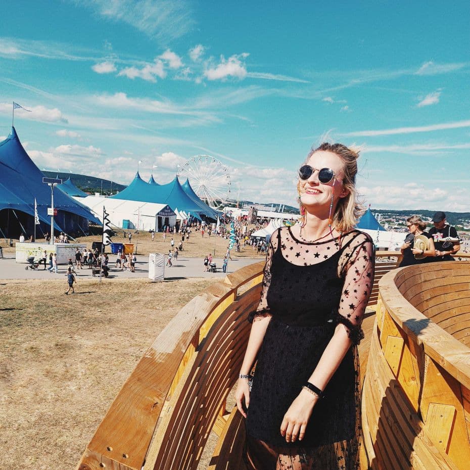 Blondynka w okularach przeciwsłonecznych na tle namiotów festiwalu muzycznego i niebieskiego nieba